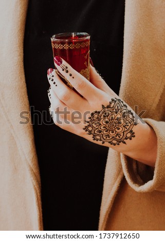 Henna Mandala on hand holding Red Moroccan Tea Glass