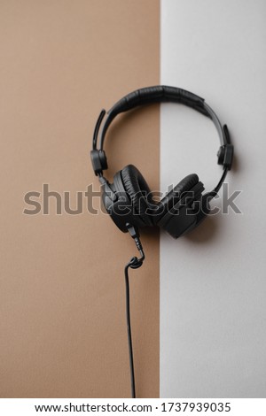 Flat lay composition with black studio headphones  on brown background, podcasting concept.
