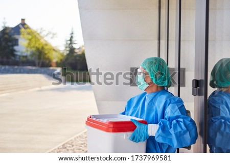 Doctor or surgeon with organ transport after organ donation for surgery in front of clinic entrance in protective clothing Royalty-Free Stock Photo #1737969581