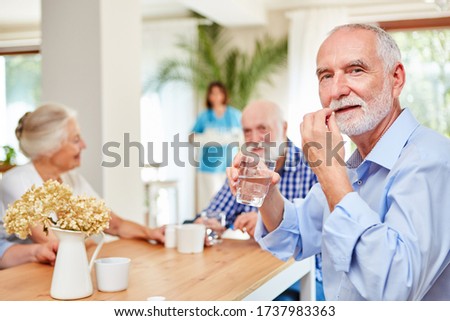 Senior man takes tablet with a sip of water at the retirement home