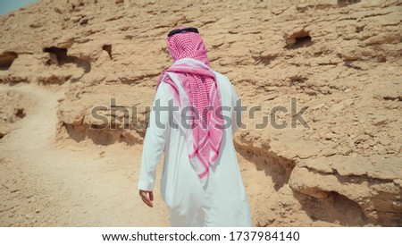 Man in traditional Arabian clothing walking in the desert. Saudi Arabia
 Royalty-Free Stock Photo #1737984140