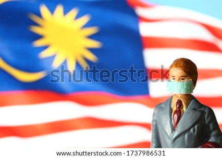 Miniature figure businessman model wearing mask and flag background scene.
