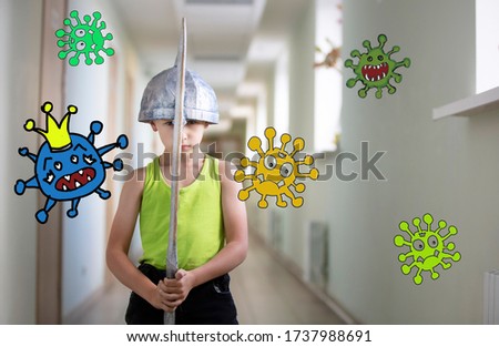 A little boy stays at home with a sword to protect against the coronavirus covid-19 virus. Fight the coronavirus epidemic. A child is fighting a caricature of a virus.