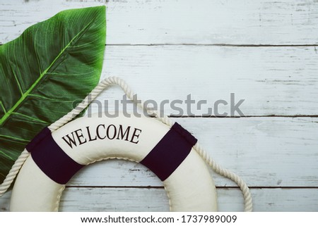 Lifebouy and tropical green leaf on wooden background