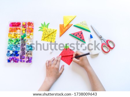 Bookmark for a child book to school. Origami paper craft with children's hands. Summer fruit tropics.