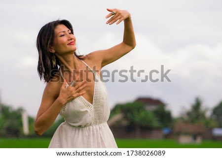 outdoors holidays portrait of attractive and happy middle aged Asian Korean woman in white dress enjoying freedom and nature at green field landscape carefree and cheerful