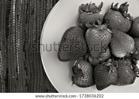 Black and white picture of strawberries on a white plate.