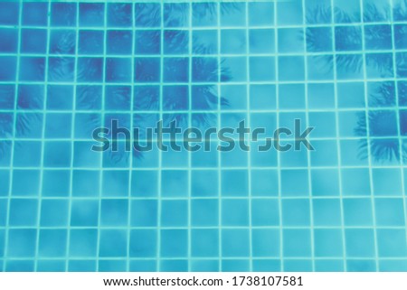 Palm trees reflection in the turquoise pool. Multipurpose backdrop. Luxury vacation, relaxation, swimming pool concept. Toned image, place for text, soft focus