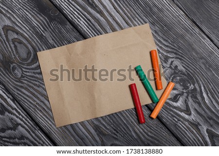 Pastel for drawing and a sheet of paper. Sticks of different colors. They lie on pine boards painted with white and black paint.