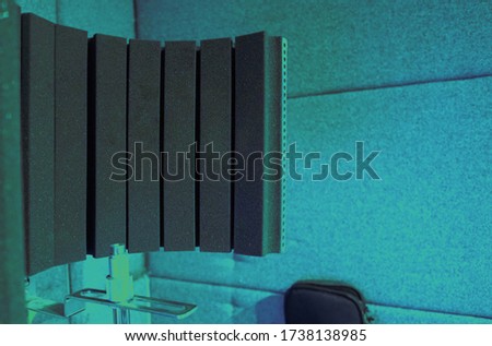 Electronics Reflexion Filter on tripod in sound production recording studio which use for reduce room ambience in untreated Recording spaces of vocalist, narrator brodcasting or live online channel 