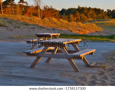 Wooden cafe tables by the sea at sunset. Blurred background.