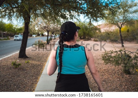 Woman walking on the side walk in a park.