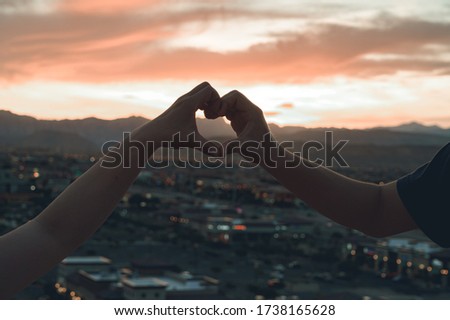 Two people combining a heart over the Las Vegas valley