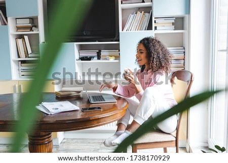 selective focus of happy african american freelancer holding cup while using laptop at home