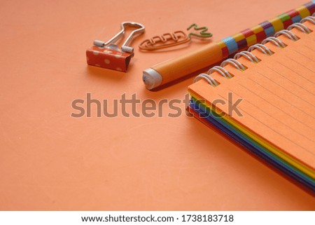  open colorful notepad and pens on orange background 