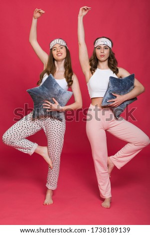 Image of a surprised optimistic young girls women friends wearing sleeping mask indoors on red background at the hen party at home.