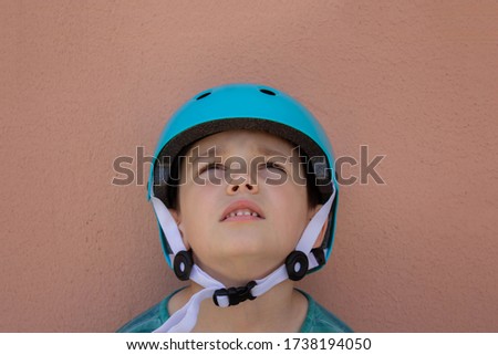 A cheerful boy in a Bicycle helmet for safety on a beige background. Ready to compete. The concept of children's sports
