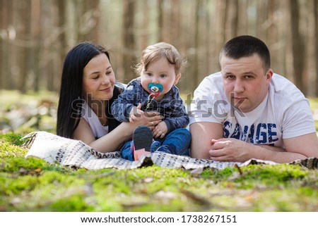 happy family in the forest. dad mom and son resting in the woods. playing with a one-year-old son.