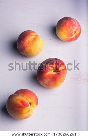 Four delicious yellow and orange peaches on a light colored background. Vertical format. Aerial view.