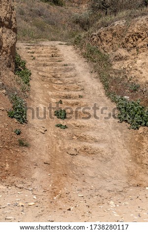 Worn steps of stone staircase are cut down by tourist along popular tourist route. Trail goes up stone stairs. Stone staircase in nature in coastal cliff. Natural stone staircase in landslide hillside