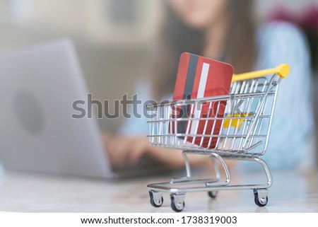 Close up photo of woman making online shopping with troley background.