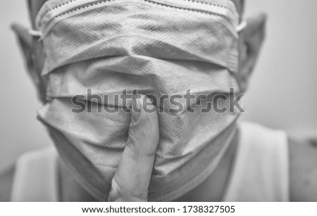 A doctor or nurse points to a medical mask on face with finger making a gesture to maintain silence. The need for and prevention of precautions for the coronavirus covid-19. Template for promotion.