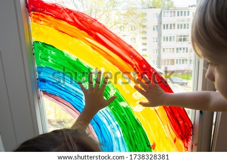 Children touches painting rainbow on the window. Stay at home during coronavirus pandemic. Social media campaign for coronavirus prevention, chase the rainbow flashmob