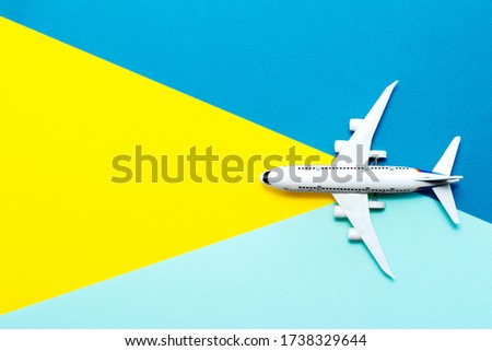 Travel concept. Miniature toy plane is traveling the world theme on blue yellow background.