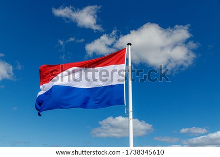 National flag of the Netherlands with horizontal tricolour of red, white and blue, Dutch flag waving on the air in a sunny day and blue sky background.