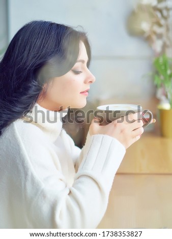 Coffee break. a Pretty Brunette girl in a white blouse, drinking coffee at a wooden table. copy space. 