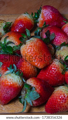 Freshly harvested seasonal organic strawberries with green leaves and natural blemishes. Experience in healthy food.