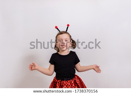 Portrait of a little girl pointing her hands to the sides in a Ladybird costume on a white isolated background with space for text.