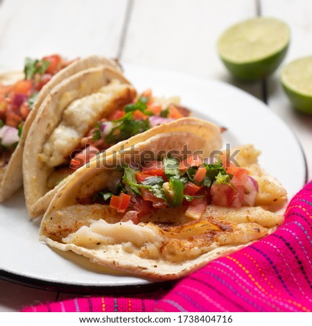 Traditional mexican fish tacos also called Baja with fresh sauce on white background