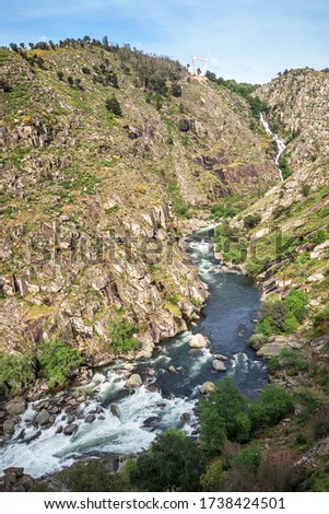 Landscape of the Paiva gorge with the Paiva river and its rapids in the foreground and the Aguieiras waterfall in the background, near Arouca in Portugal.