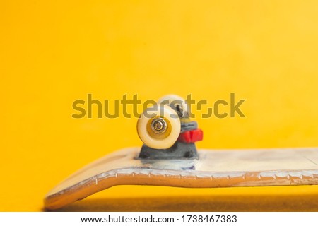 Small skateboard on yellow background. tiny skate for fingers. fingerboard close up. home leisure concept. copy space