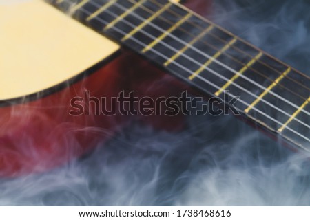 Defocused guitar in smoke abstract background. musical instrument. strings on the guitar fretboard. focus on foreground