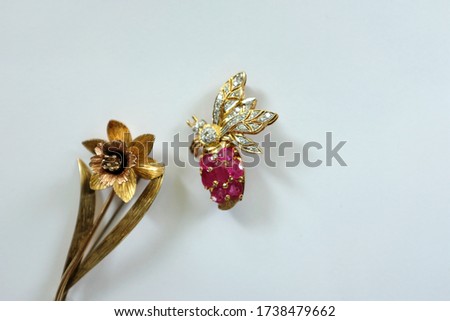 A daffodil flower and a bee vintage brooches isolated on a white background. Top view.