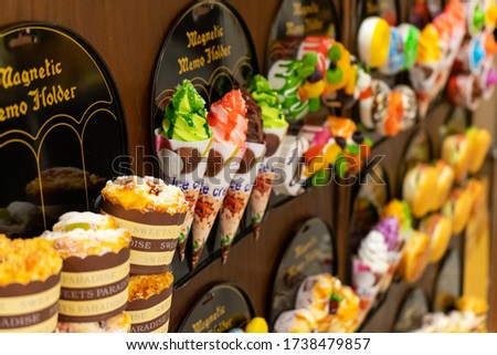 Colorful and bright decorative magnets in the form of ice cream, cake, donut and other desserts in stock at the stand of the souvenir shop