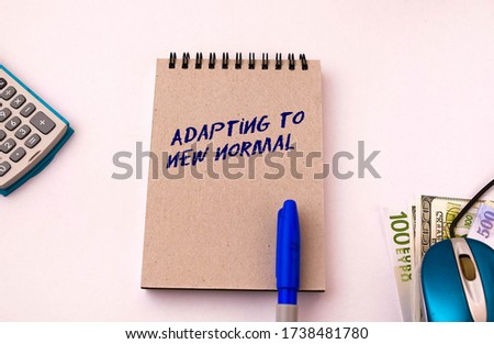 Texts embracing new normal note pad. Conceptual of adapting to new norm and lifestyle change due to  Covid-19. Calculator, pen and mouse on right in visibility.  Selective focus on note pad cover. Royalty-Free Stock Photo #1738481780