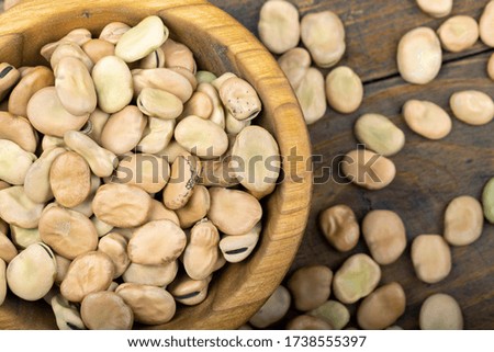 dry beans in a wooden plate and sprinkled on a wooden background. close up, place for text
