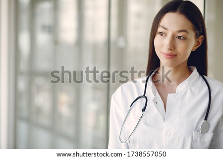 Woman in a uniform. Doctio with a stethoscope. Brunette in a hall.