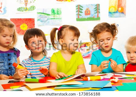 Five happy little 3-4 years old kids sitting by the table on creative paint an glue lesson Royalty-Free Stock Photo #173856188