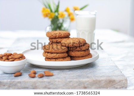 Tasty oatmeal almond cookies with jar of milk on the old marble table beautiful close-up picture light white background. Homecooking delicious food