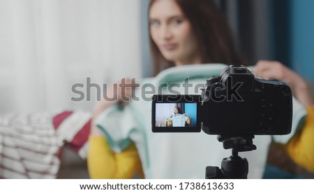 Woman making video blog about fashion wardrobe or sales online trying clothes on, focus on camera