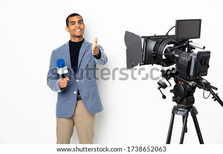 Reporter African American man holding a microphone and reporting news over isolated white background shaking hands for closing a good deal Royalty-Free Stock Photo #1738652063