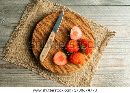 Top view of rresh organic strawberries with knife on wooden cutting board. Rustic style. 