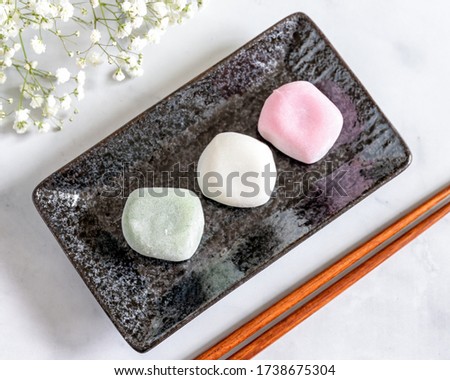 View from the top of Different Flavors of Mochi on a black rectangular plate and Baby Breath Flowers Background Blur
