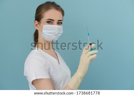 a doctor in a mask and gloves holds a syringe in his hands