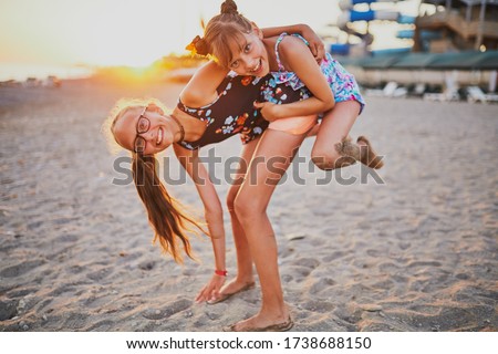 Two sisters playing on the beach at sunset. Against the background of the water park.