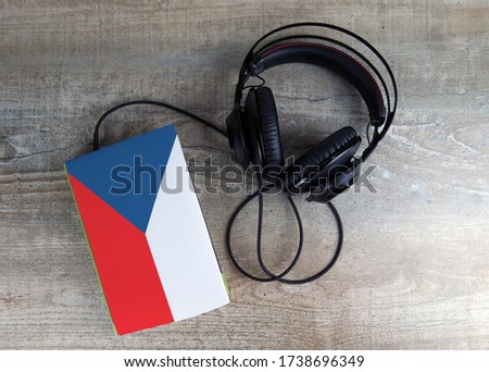 Headphones and book. The book has a cover in the form of Czech flag. Concept audiobooks. Learning languages.